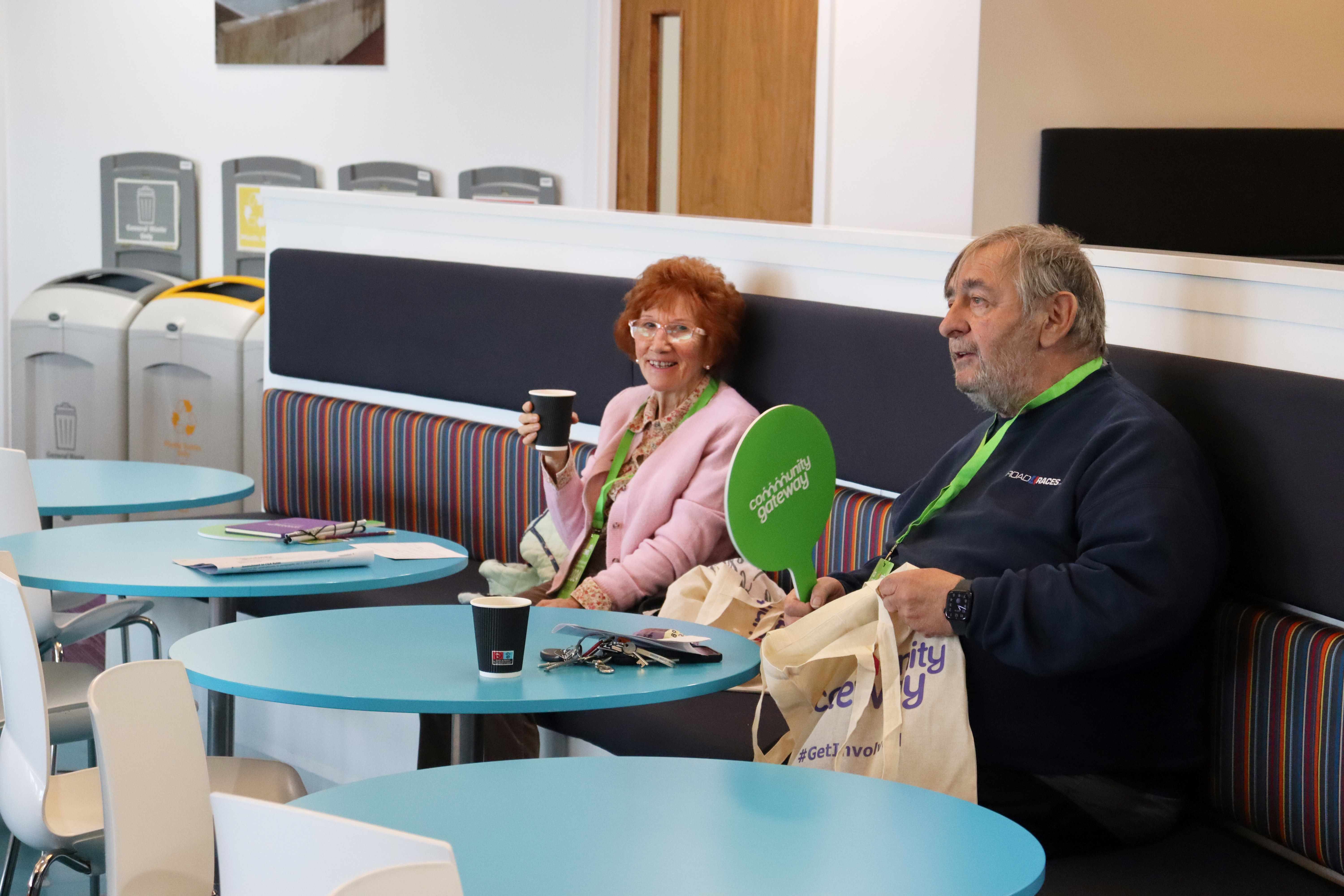 Two tenants sitting at a table smiling holding paddles for voting