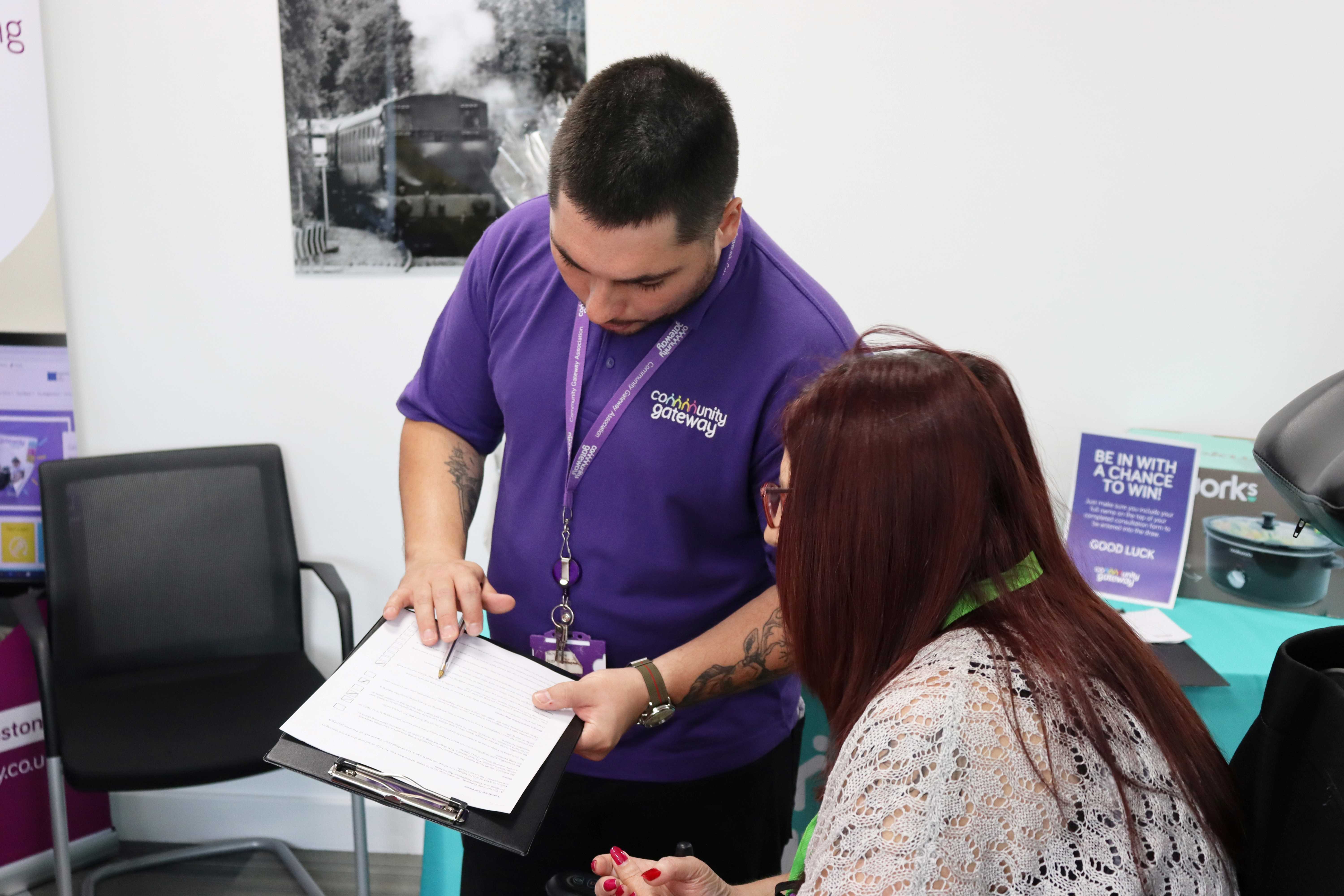 A member of CGA staff with a piece of paper on a clipboard, completing a form with a tenant