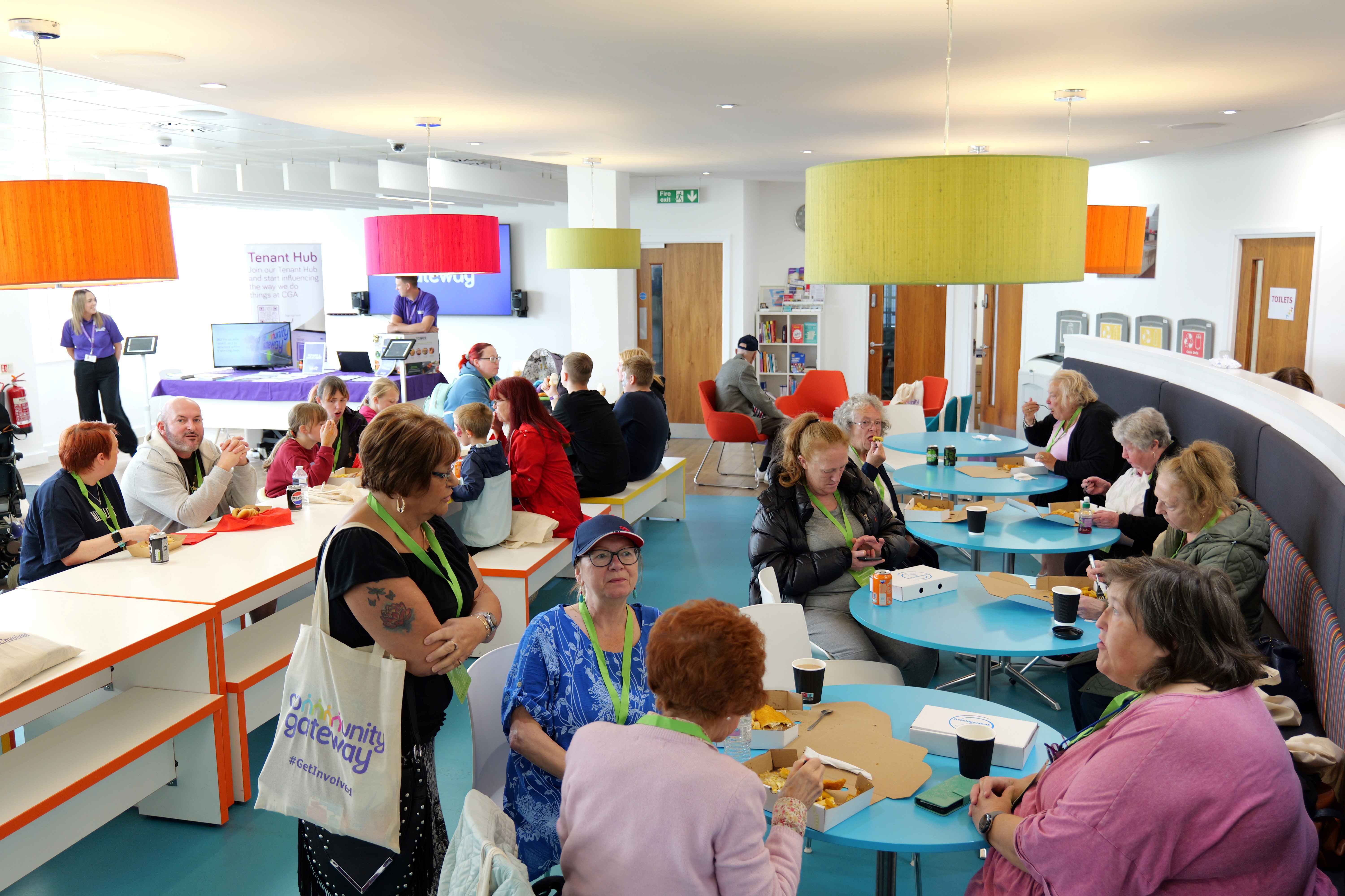 A large group of people in a bright, colourful room talking between themselves