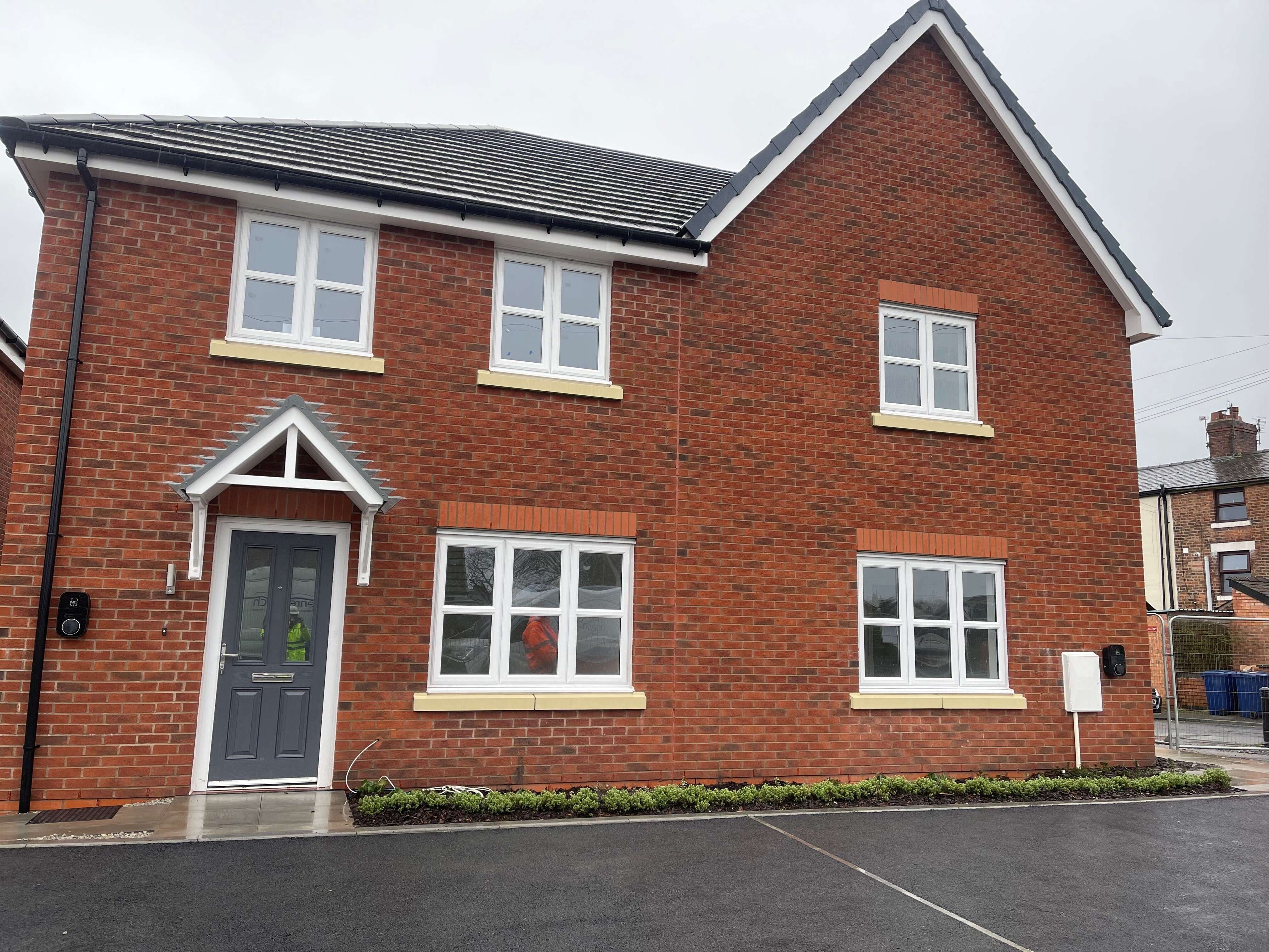 Red brick house with 5 windows and a grey front door