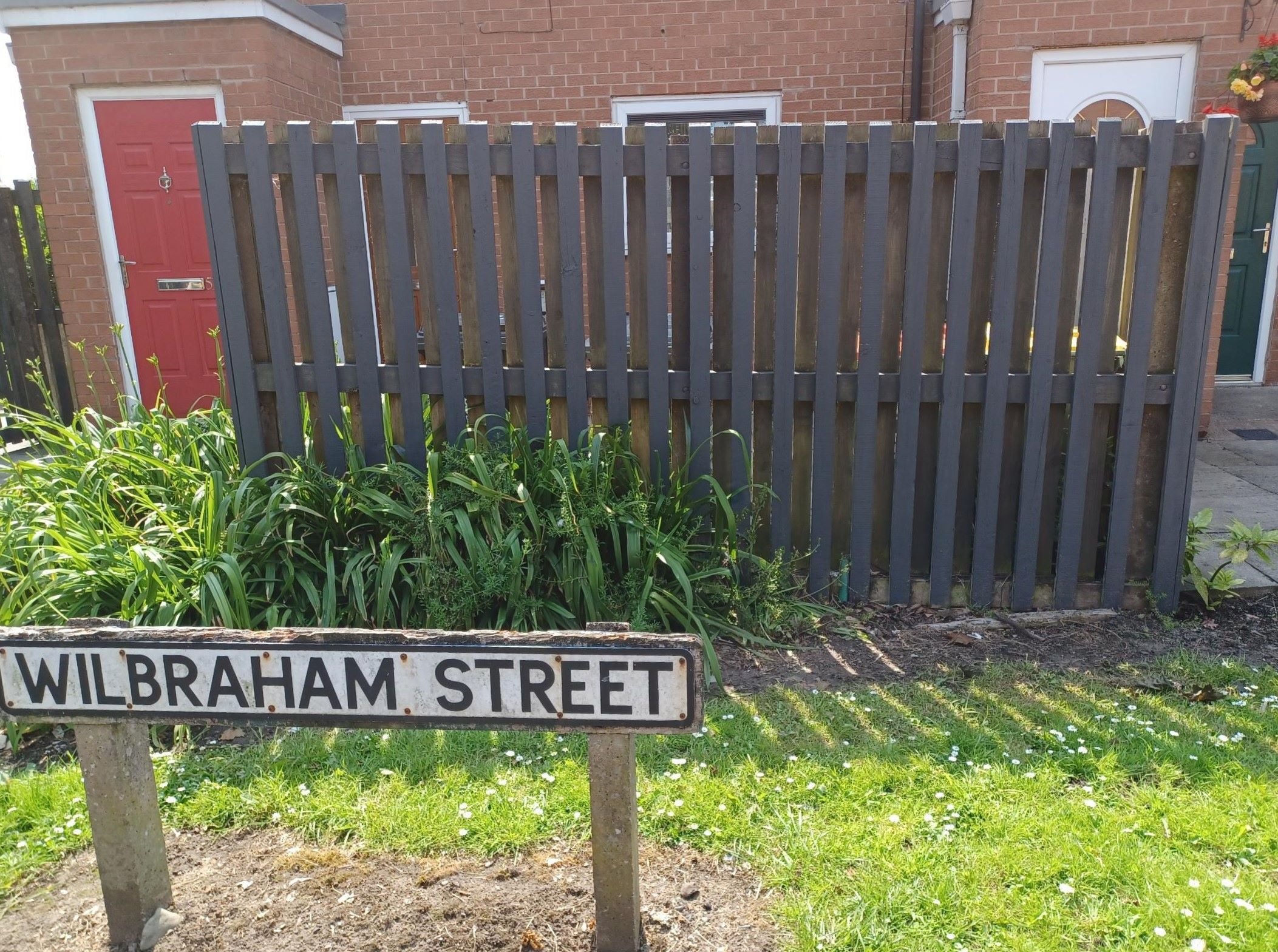 An after image of a fence with a street sign in front saying Wilbraham street