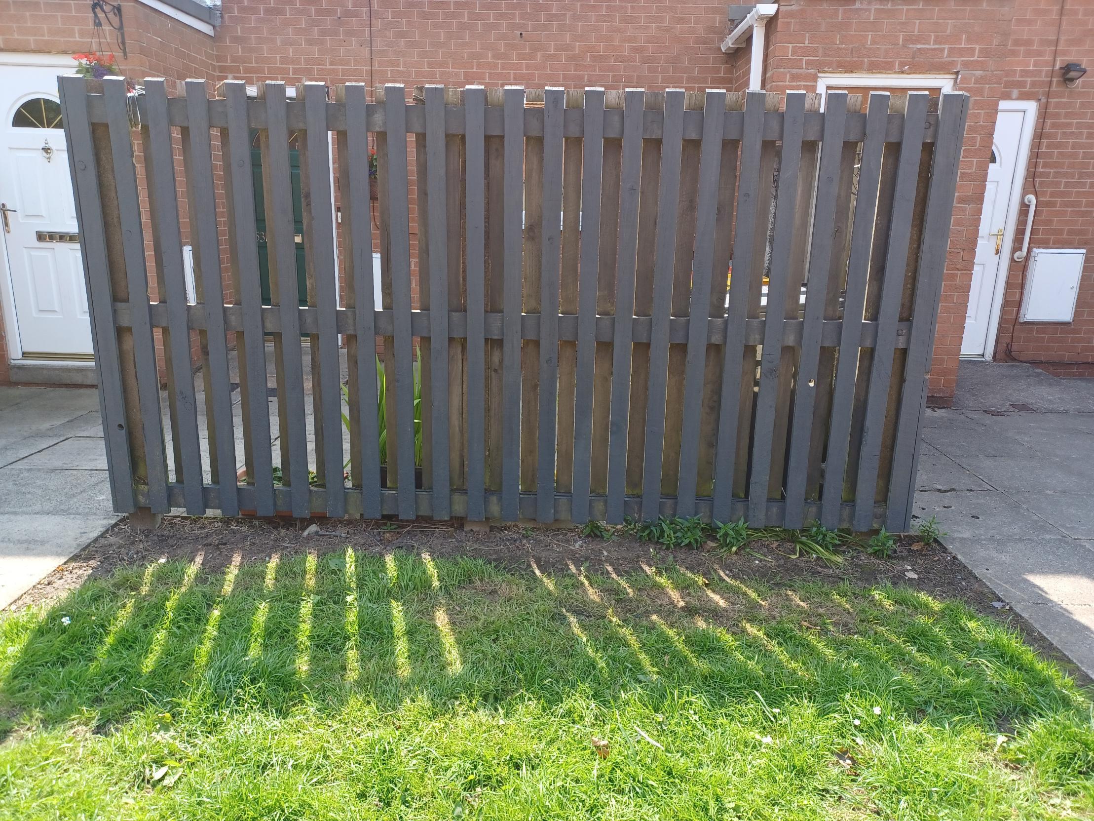 A freshly painted fence in front of a red brick property