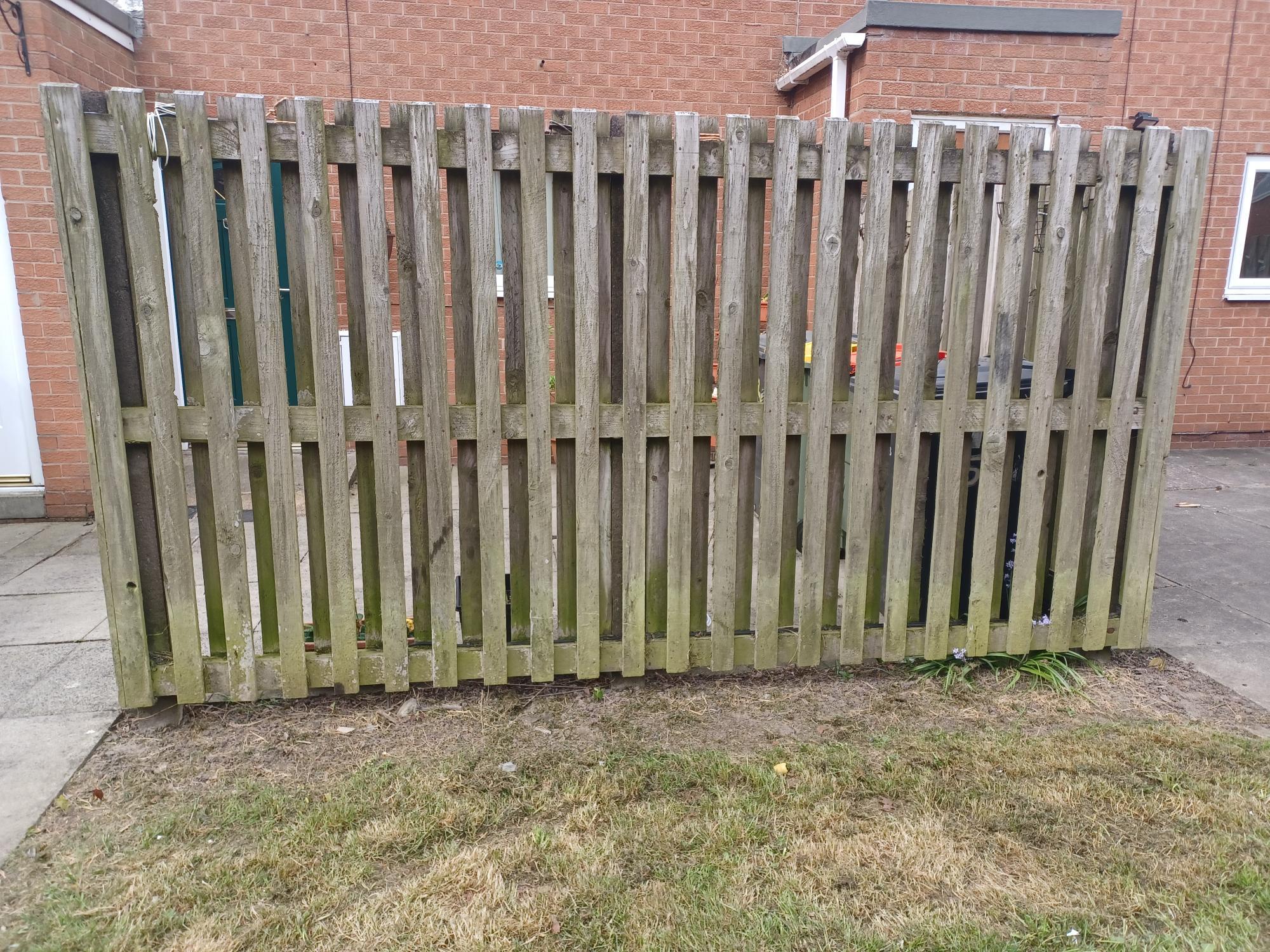 A bare fence in front of a red brick property