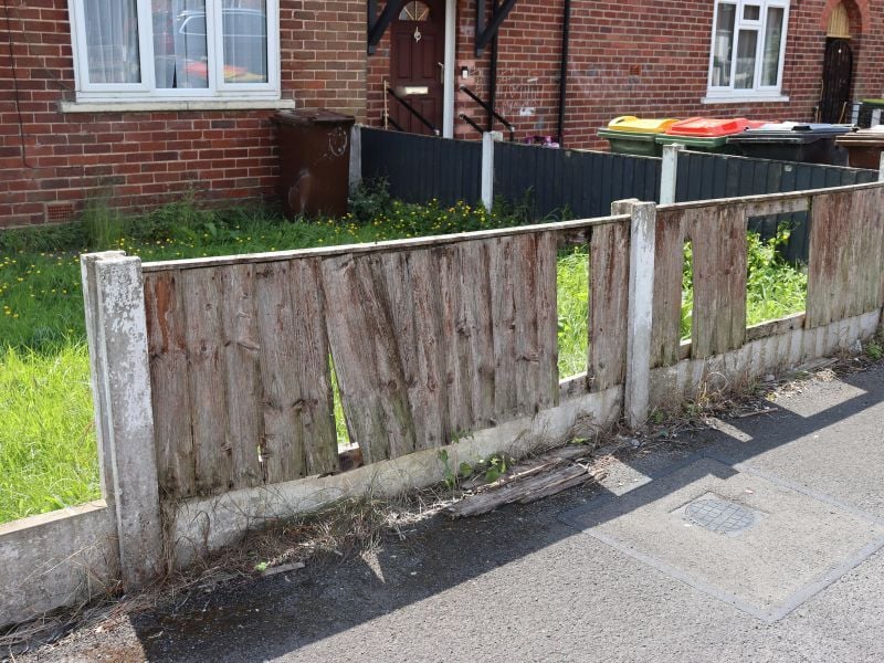 A broken fence with panels missing