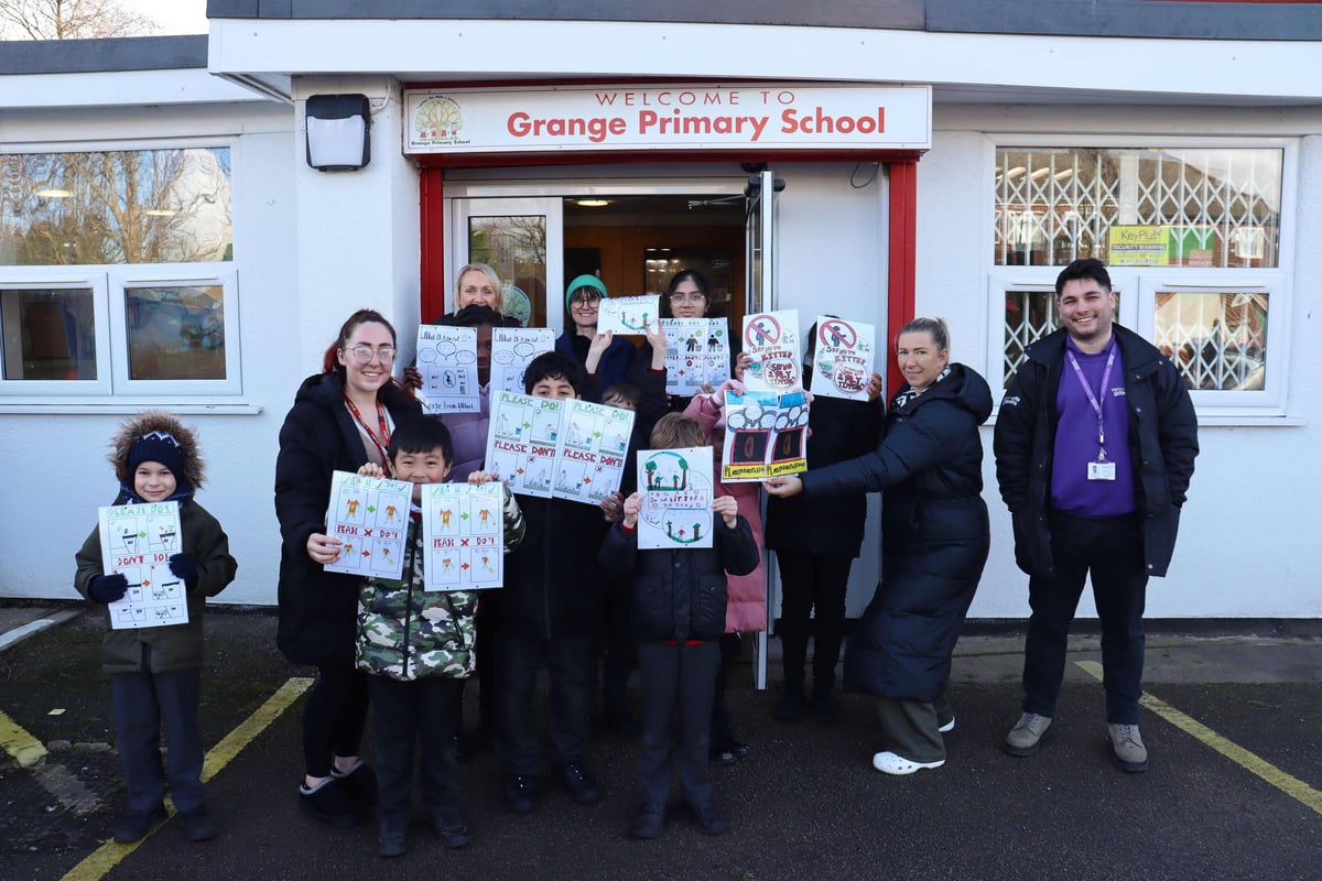 Group photo of adults and children holding hand drawn posters