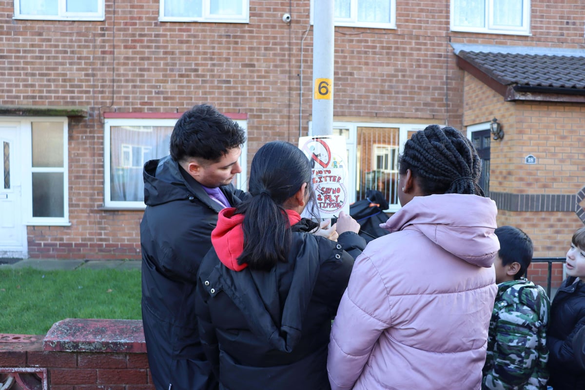 Man and two young girls putting up a hand drawn poster