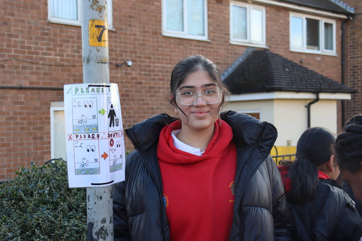 Young girl stood next to a lamp post with a hand drawn poster attached