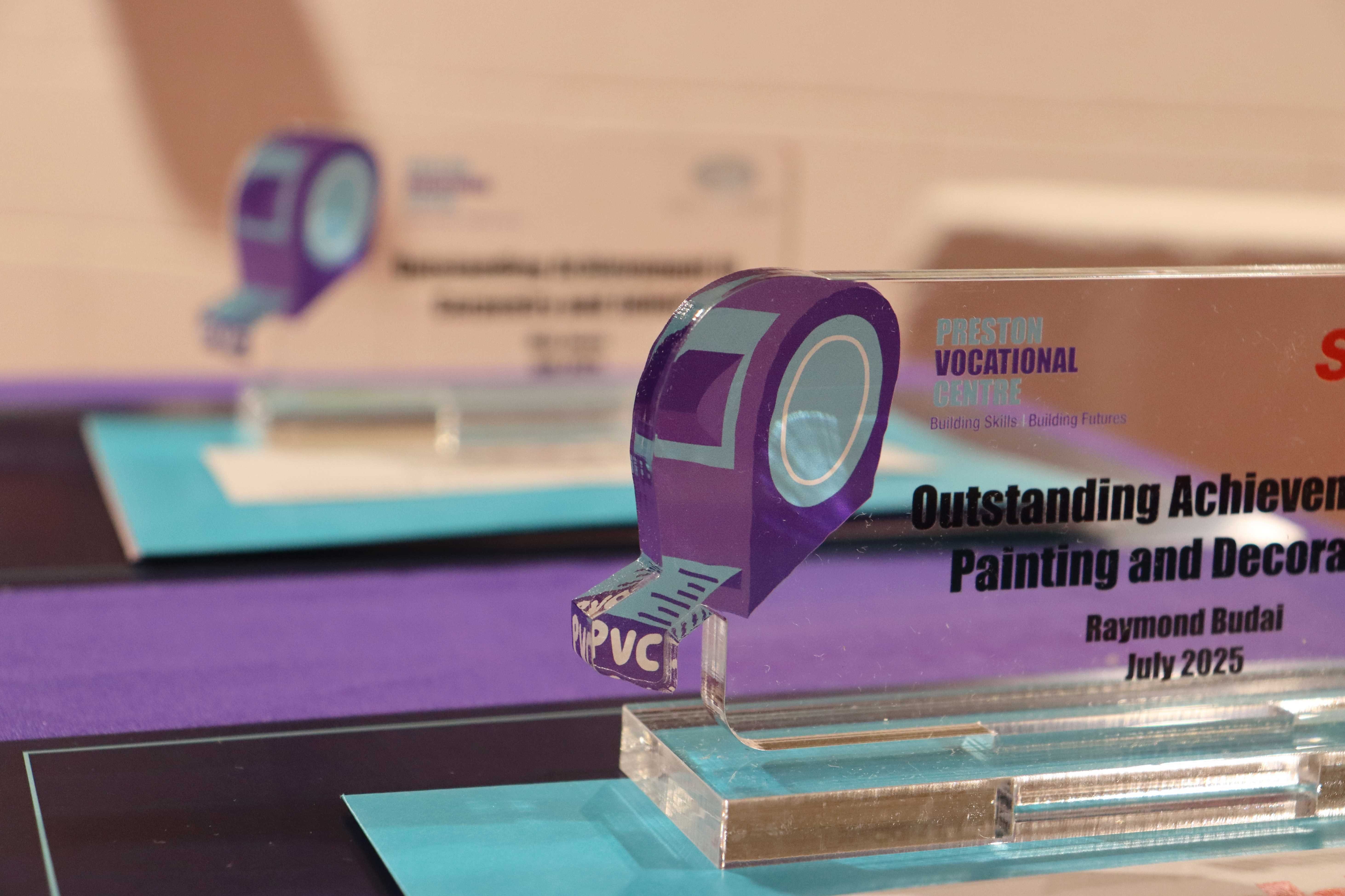 Close up picture of the trophies focusing on the PVC tape measure logo on the top left edge